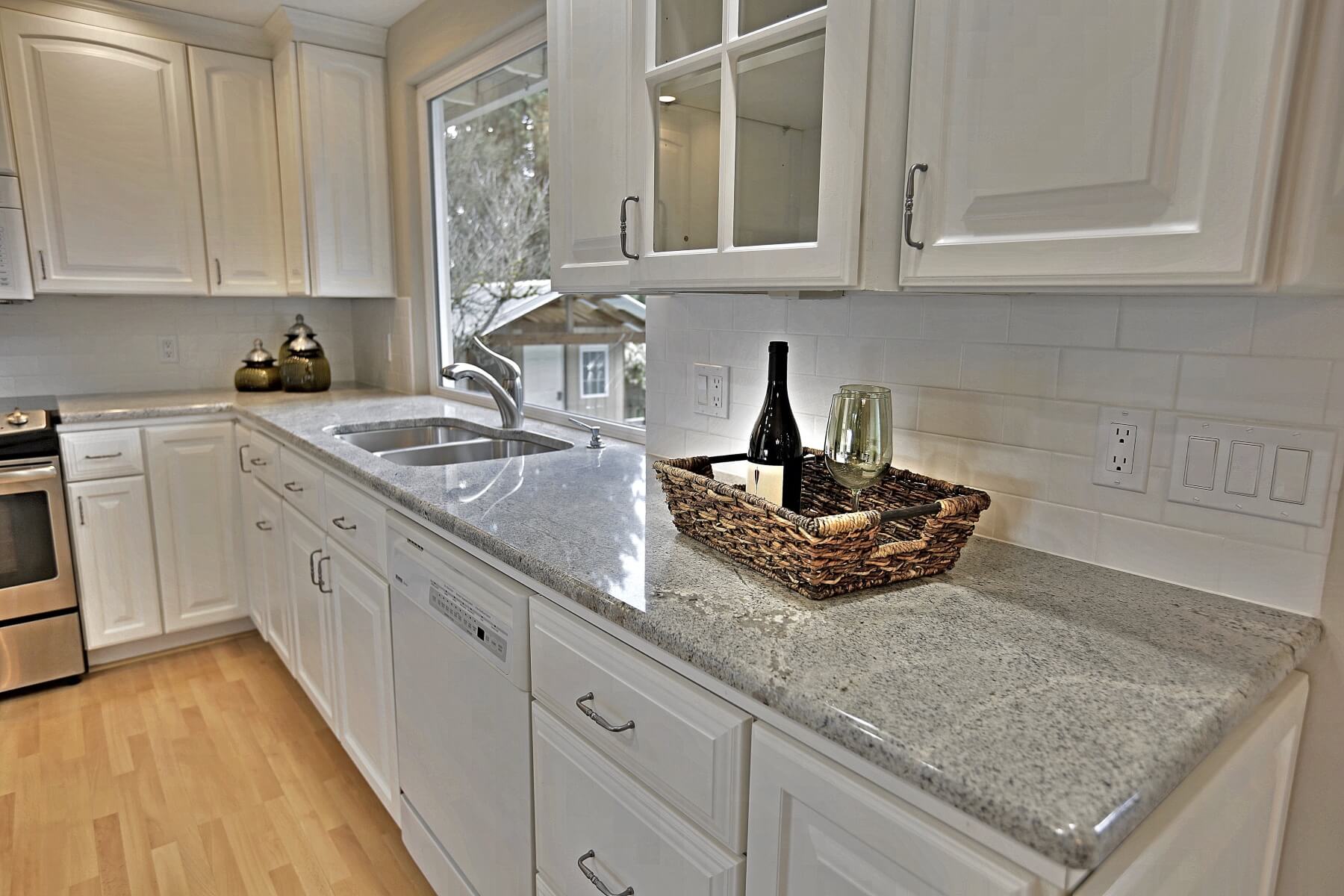 Modern kitchen featuring a quartz counter top and a wine bottle in a basket with wine glasses